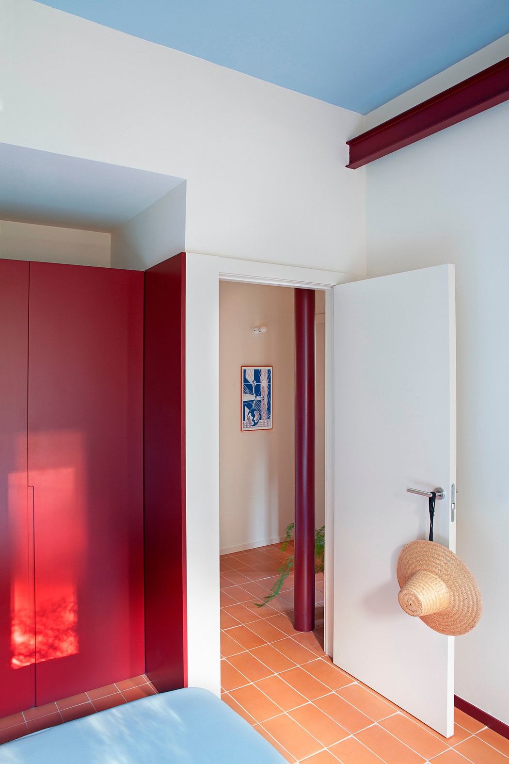 Bright hallway with red accents and terracotta floor tiles.