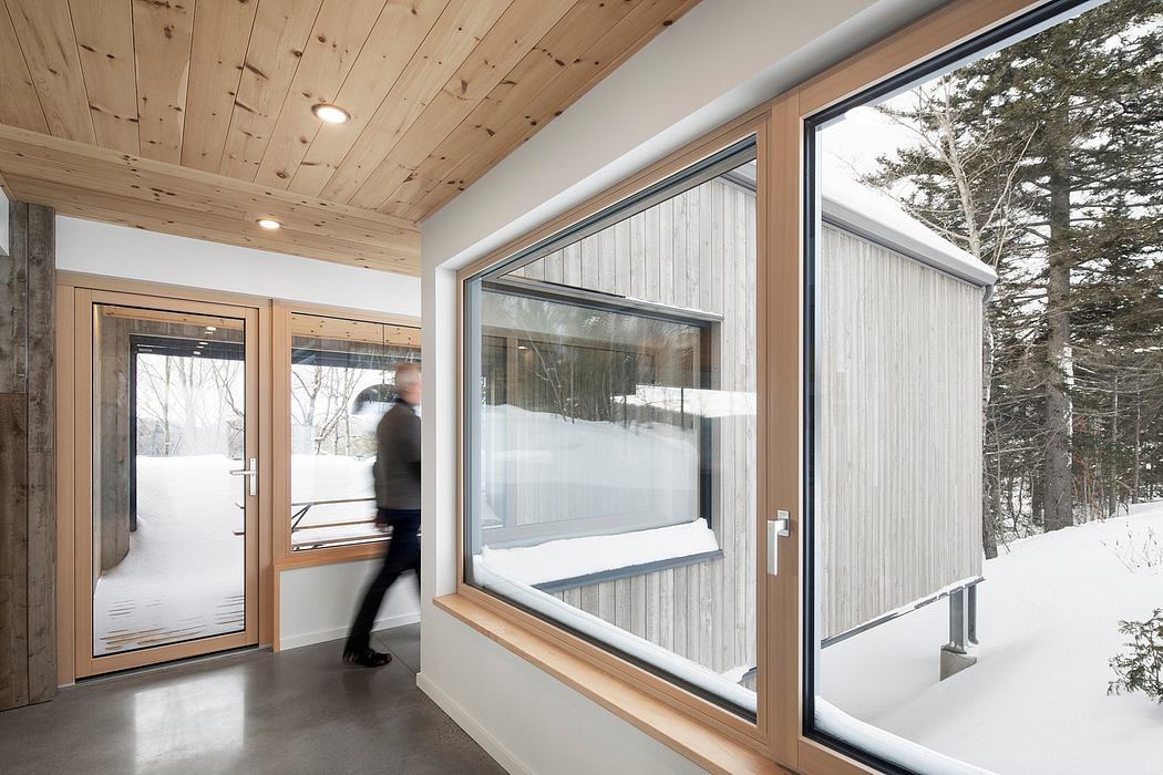 Contemporary hallway with wooden ceiling and large windows overlooking snow.