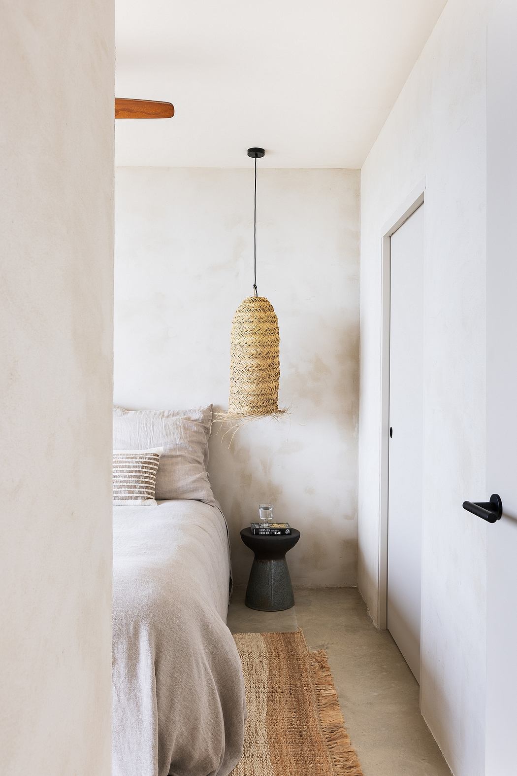 Minimalist bedroom with textured pendant light and neutral palette.