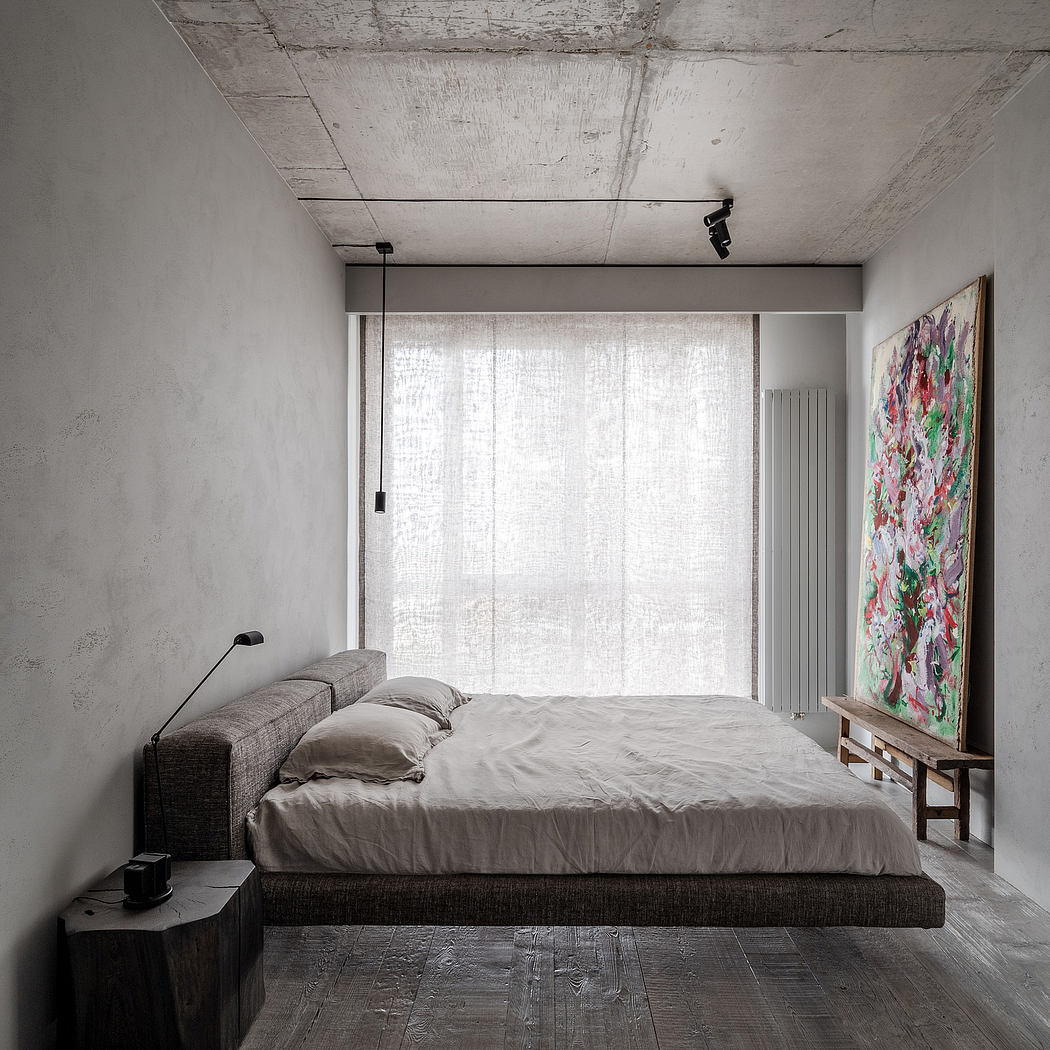 Minimalist bedroom with exposed concrete and large floral art.