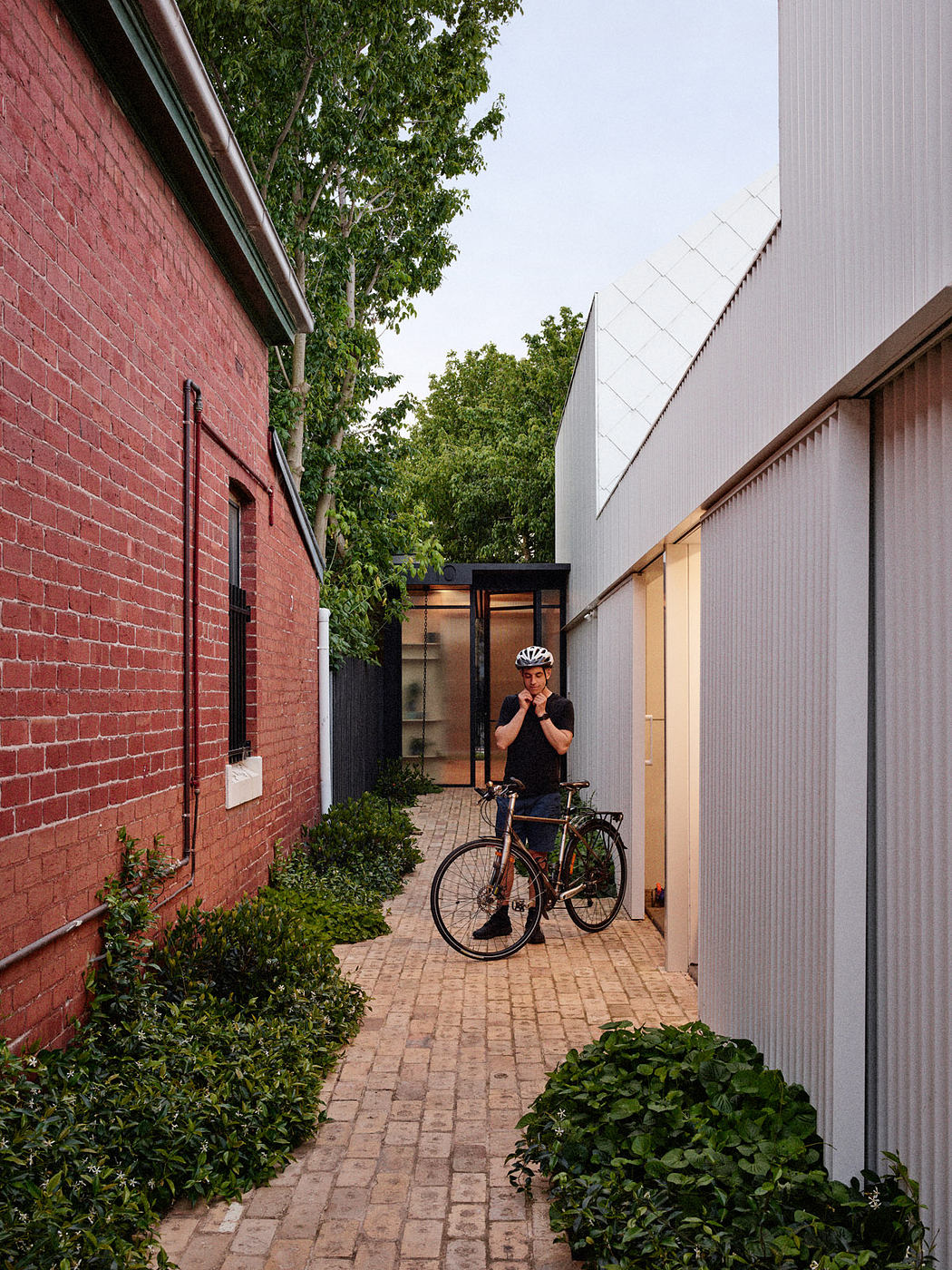 Urban alley with cyclist, red brick wall, and metal siding.