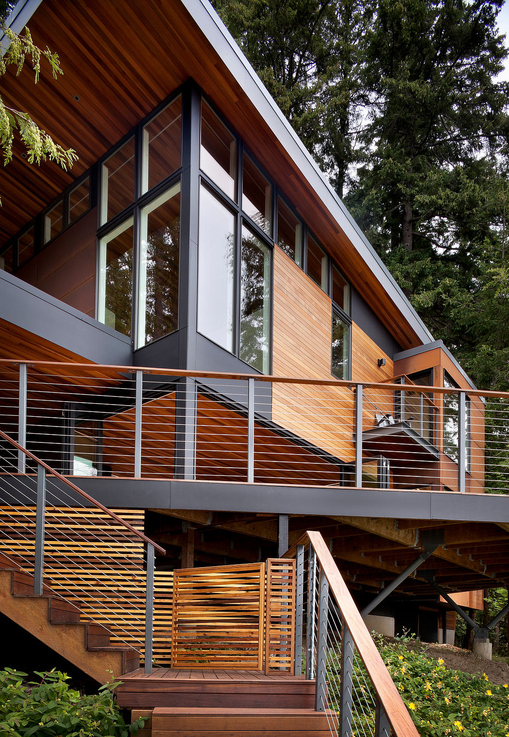 Contemporary forest home with expansive windows and wooden siding.