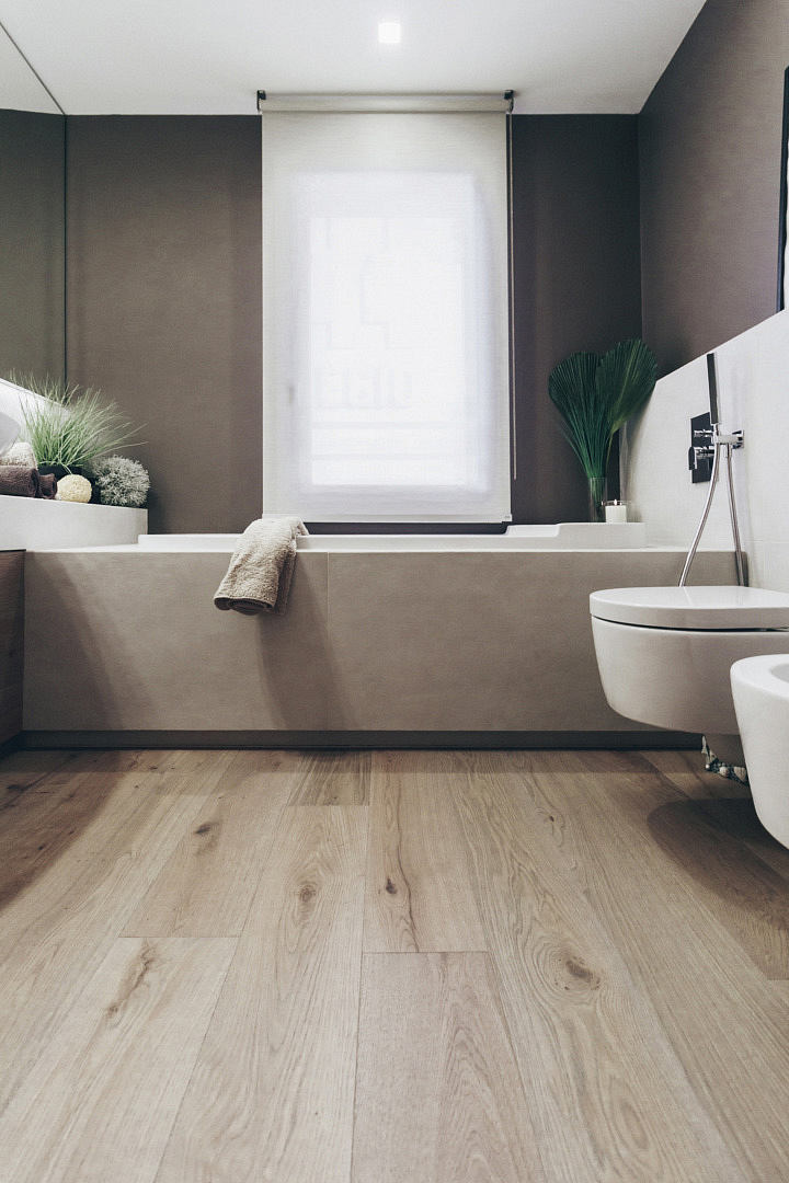 Modern bathroom with beige walls, a bathtub, and wooden floor.