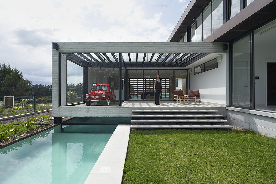 Modern home with glass patio, pool, vintage car, and a person standing.