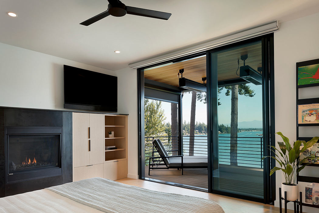 Contemporary bedroom with fireplace and waterfront view.