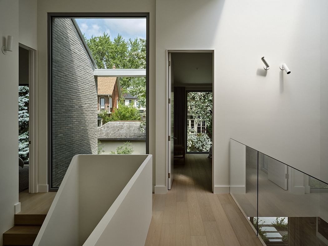 Modern home interior with staircase, large window, and view of trees.