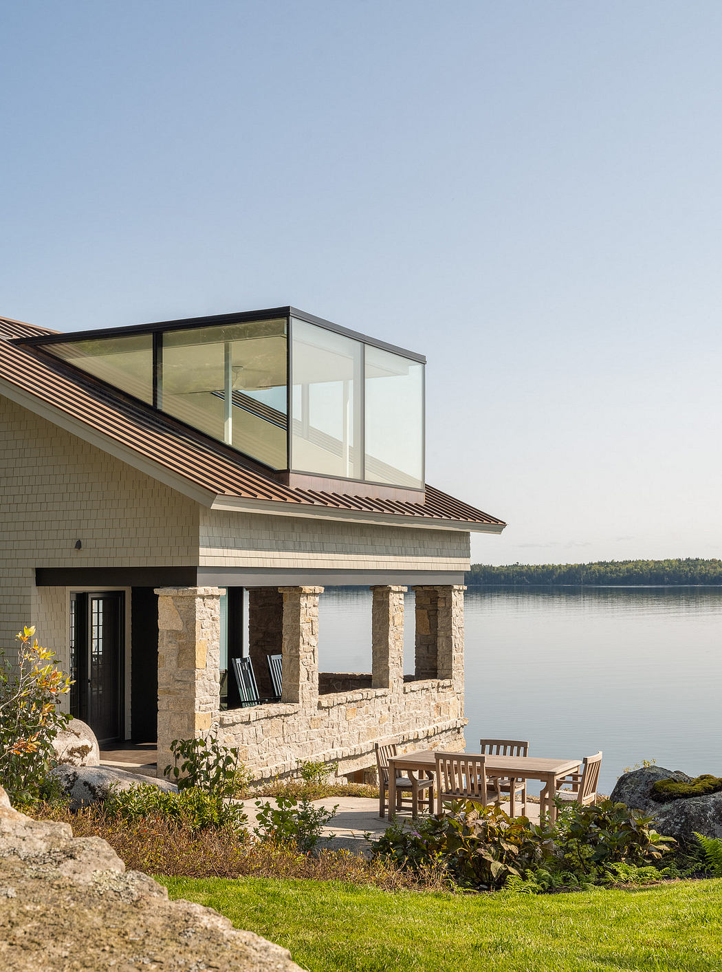 Lakeside house with large glass balcony and stone walls