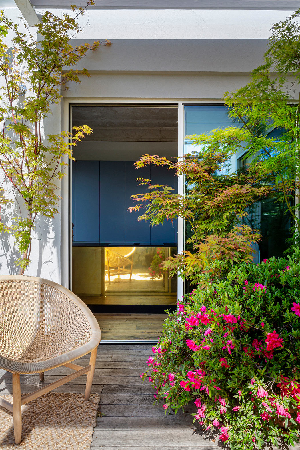 Contemporary entrance with sliding door, chair, and vibrant plants.