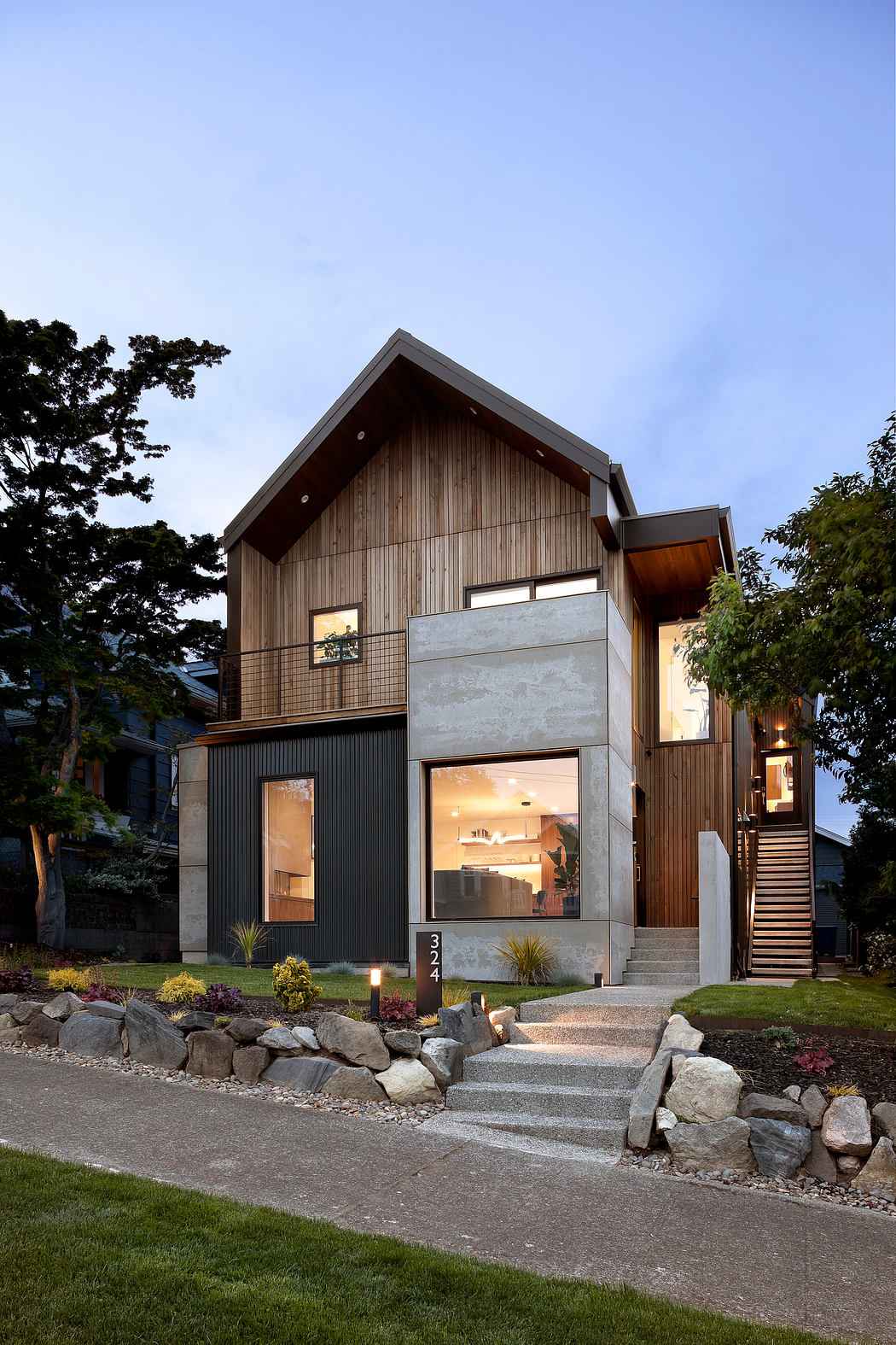Contemporary two-story home with wood and concrete exterior at dusk.