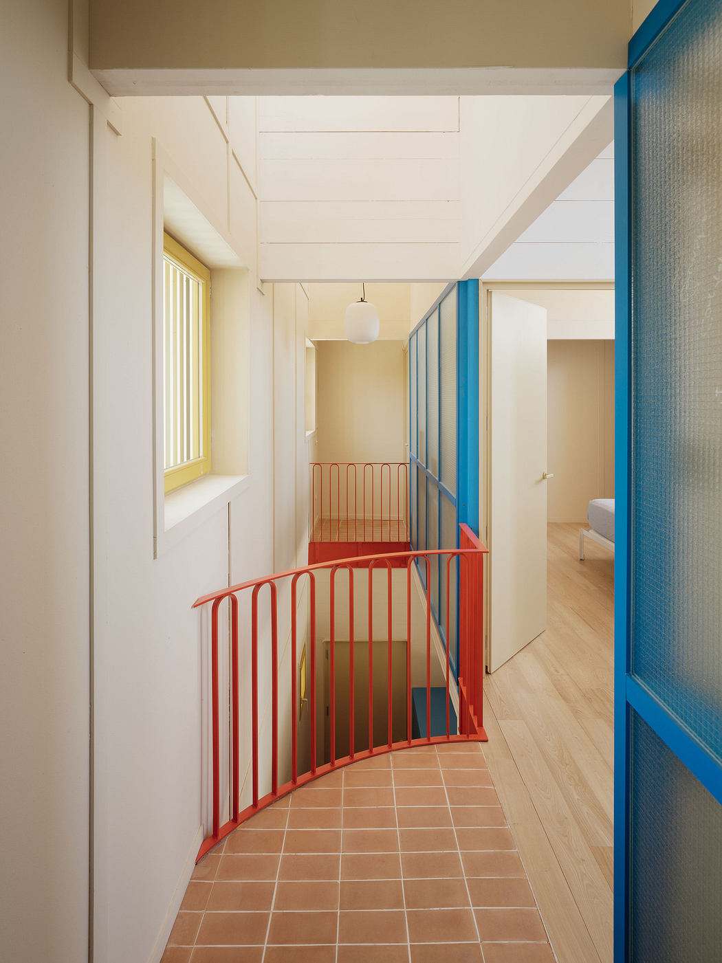 Bright interior corridor with colorful blue and red railings and translucent panels.