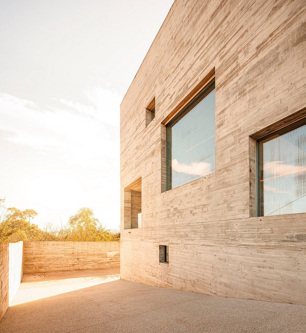 Contemporary building with textured stone facade and large windows under a clear sky.