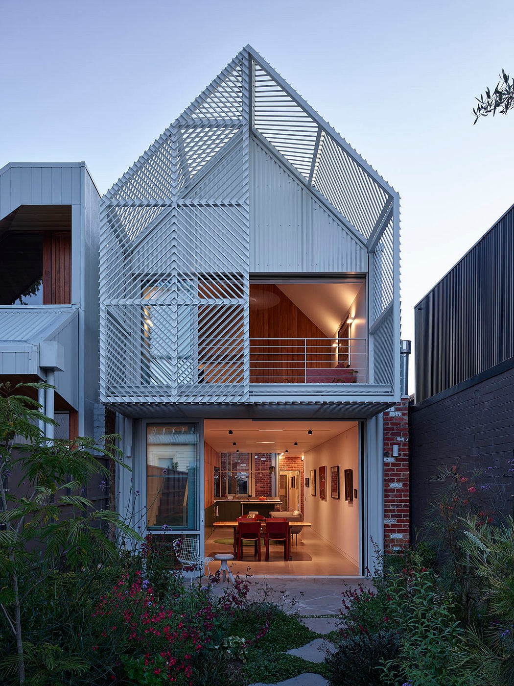 Contemporary house with geometric facade and warm interior lighting.