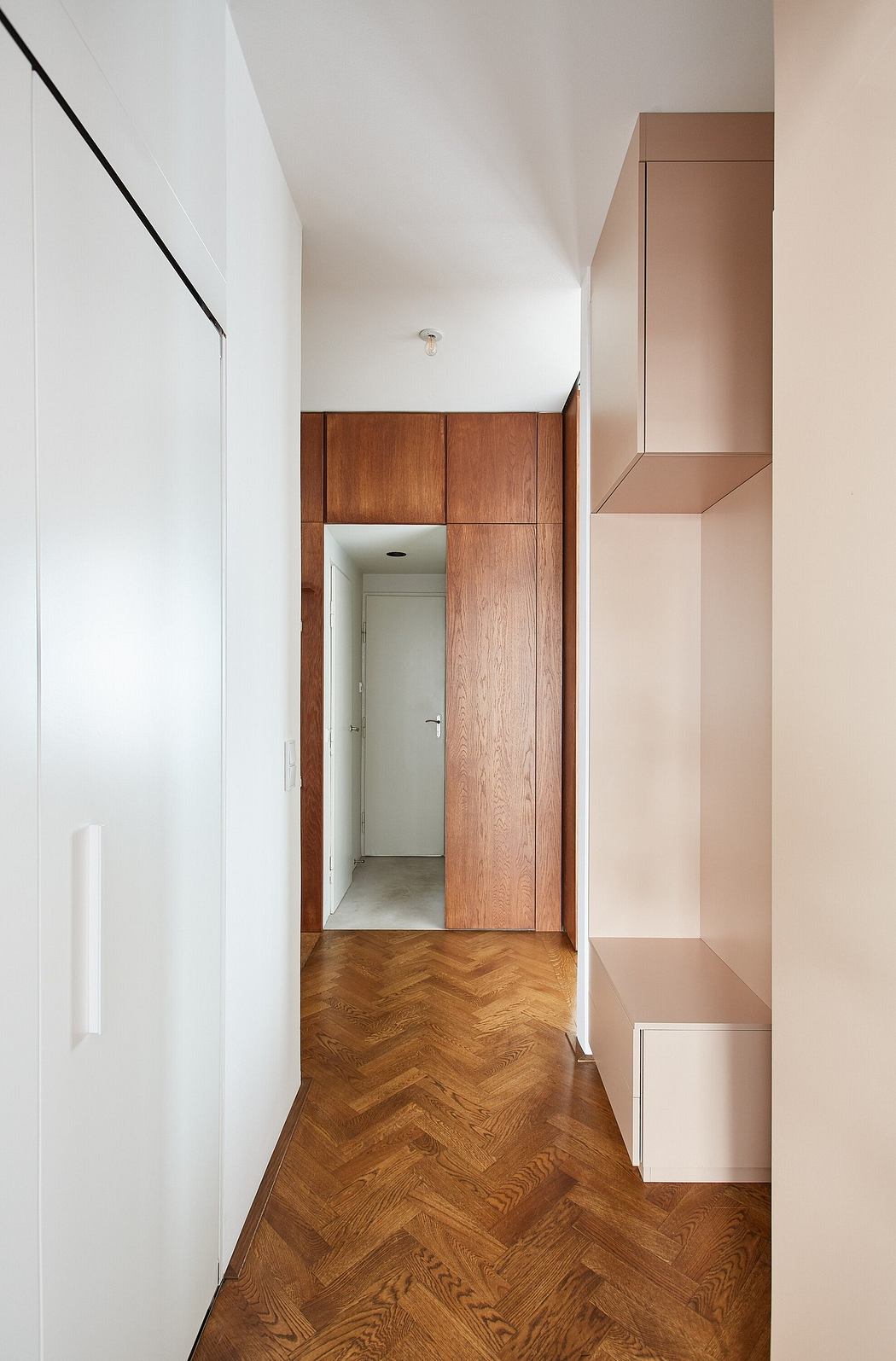 Minimalist hallway with herringbone floor and wooden accents.