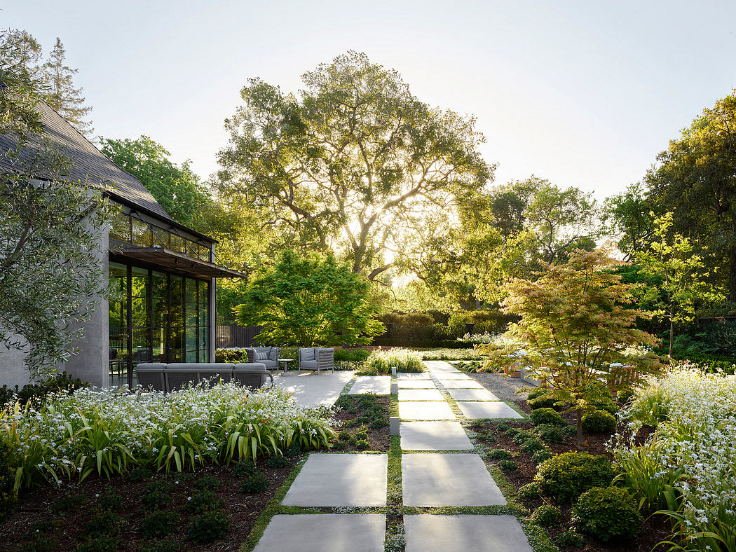 Modern home with large windows overlooks a landscaped garden at sunset.