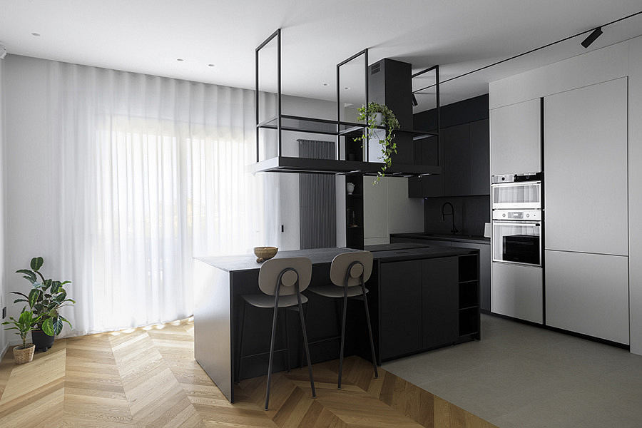 Modern kitchen with black cabinets, white walls, and wooden floor.