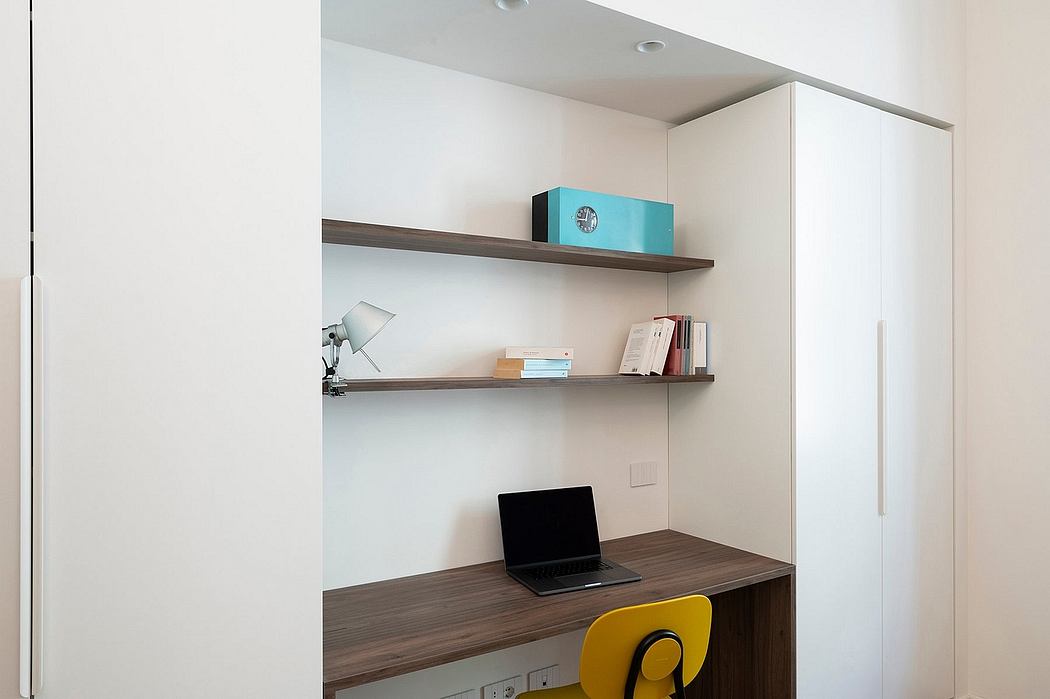 Minimalist home office nook with desk, shelves, and laptop.