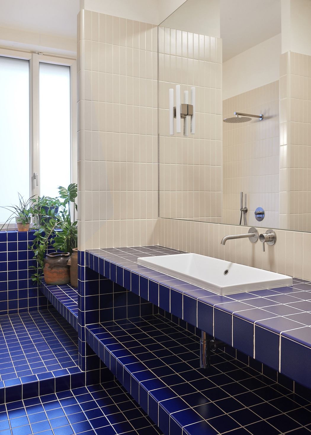 Contemporary bathroom with blue tiled countertop and white basin.