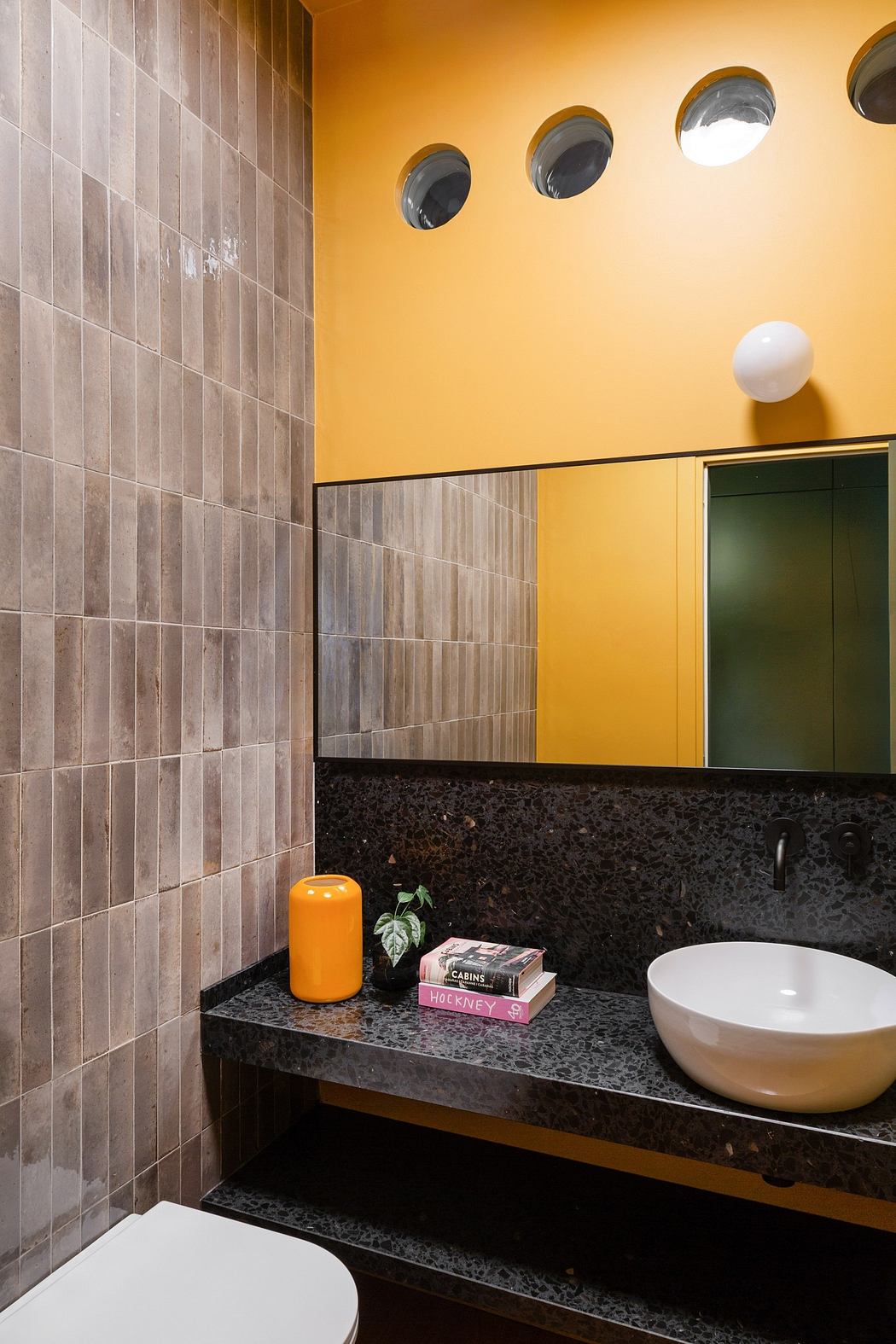 Contemporary bathroom with circular windows and yellow walls.