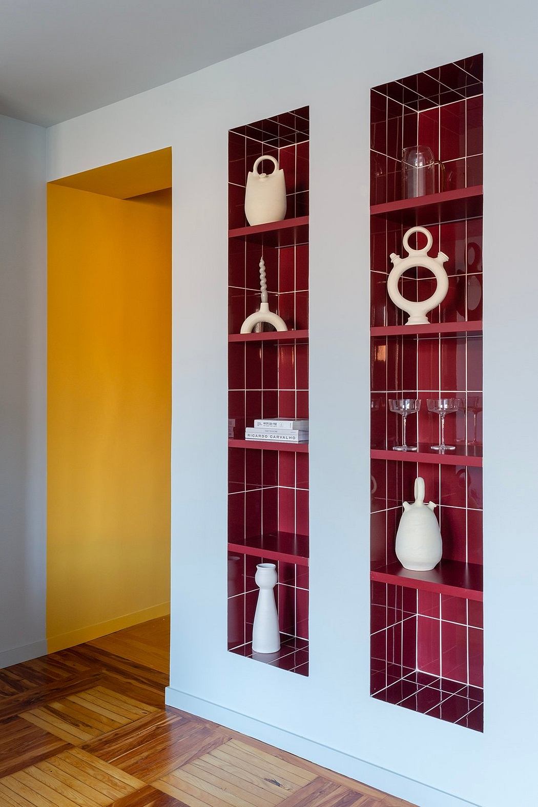 Modern room with a yellow door and a wall niche displaying white vases on red