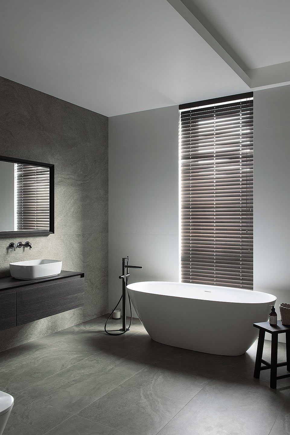 Minimalist bathroom with a freestanding tub and venetian blinds.