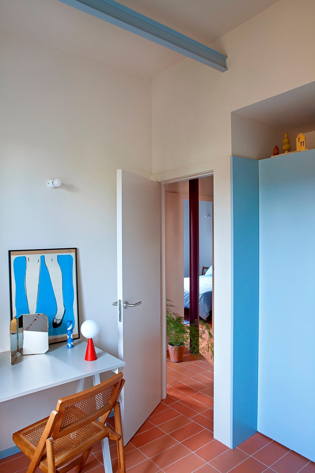 Small room with terra-cotta tiles, white walls, a blue partition, and