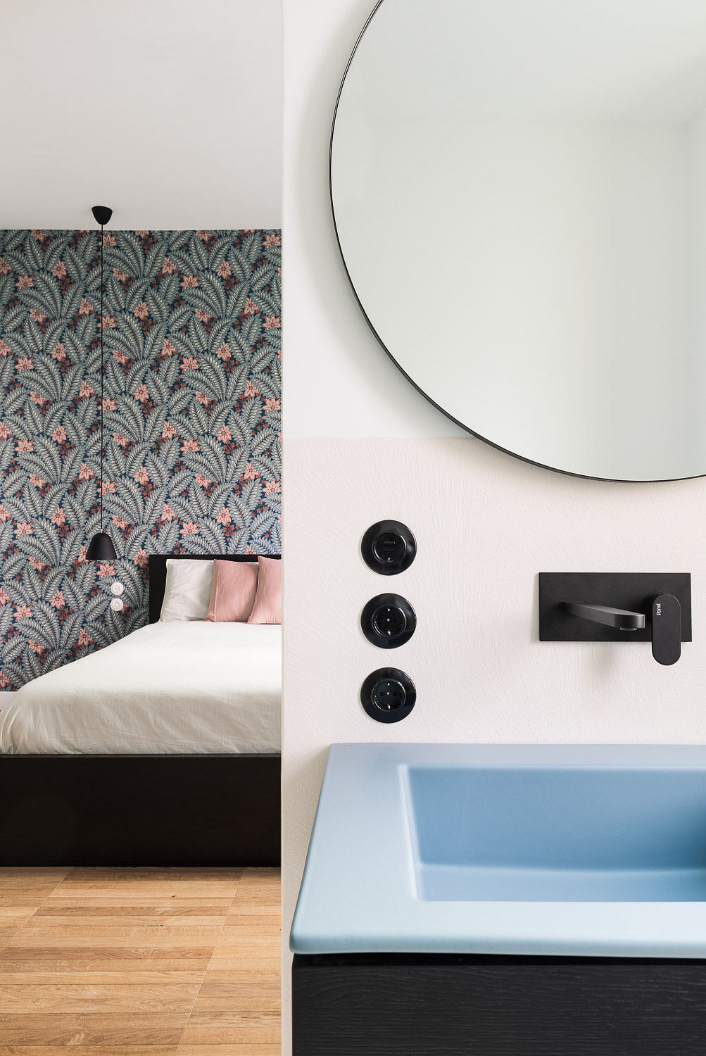 Modern interior with patterned wallpaper, round mirror and blue sink.