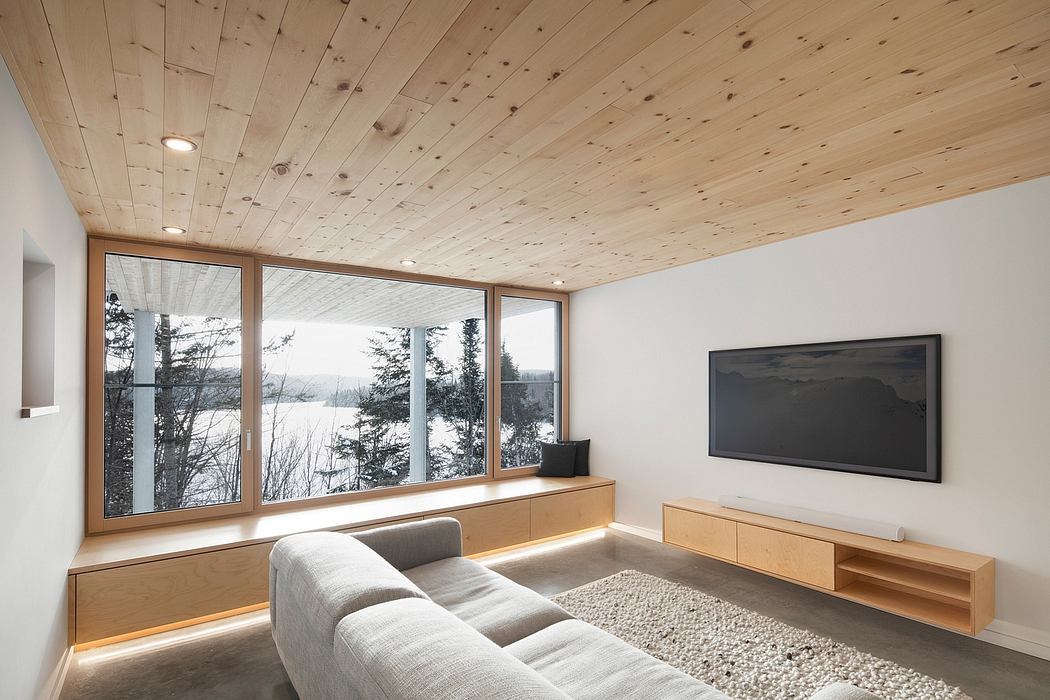 Modern living room with wooden ceiling, large window view, and minimalist furniture.