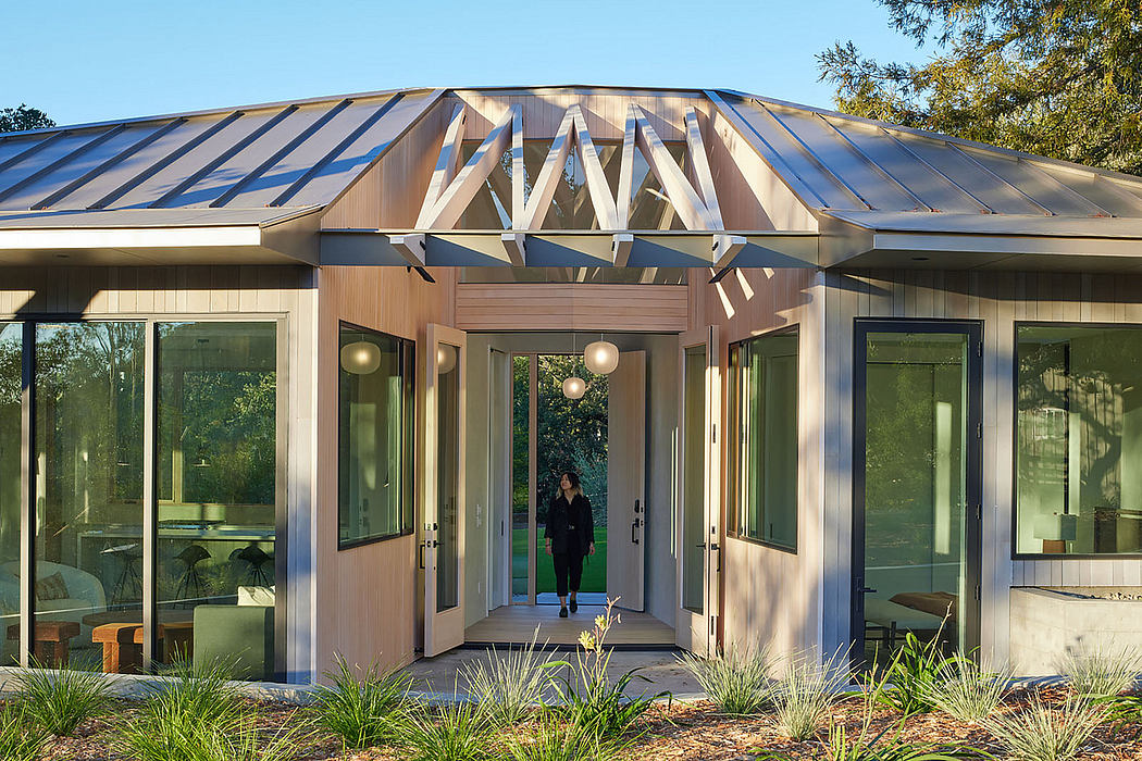 Modern house entrance with geometric roof and a person standing in the doorway.