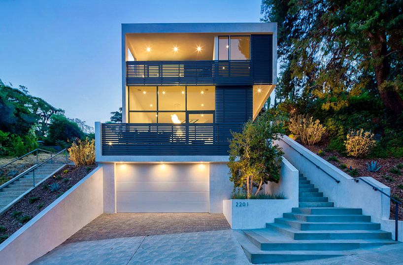 Modern two-story house with illuminated windows and exterior stairs at dusk.