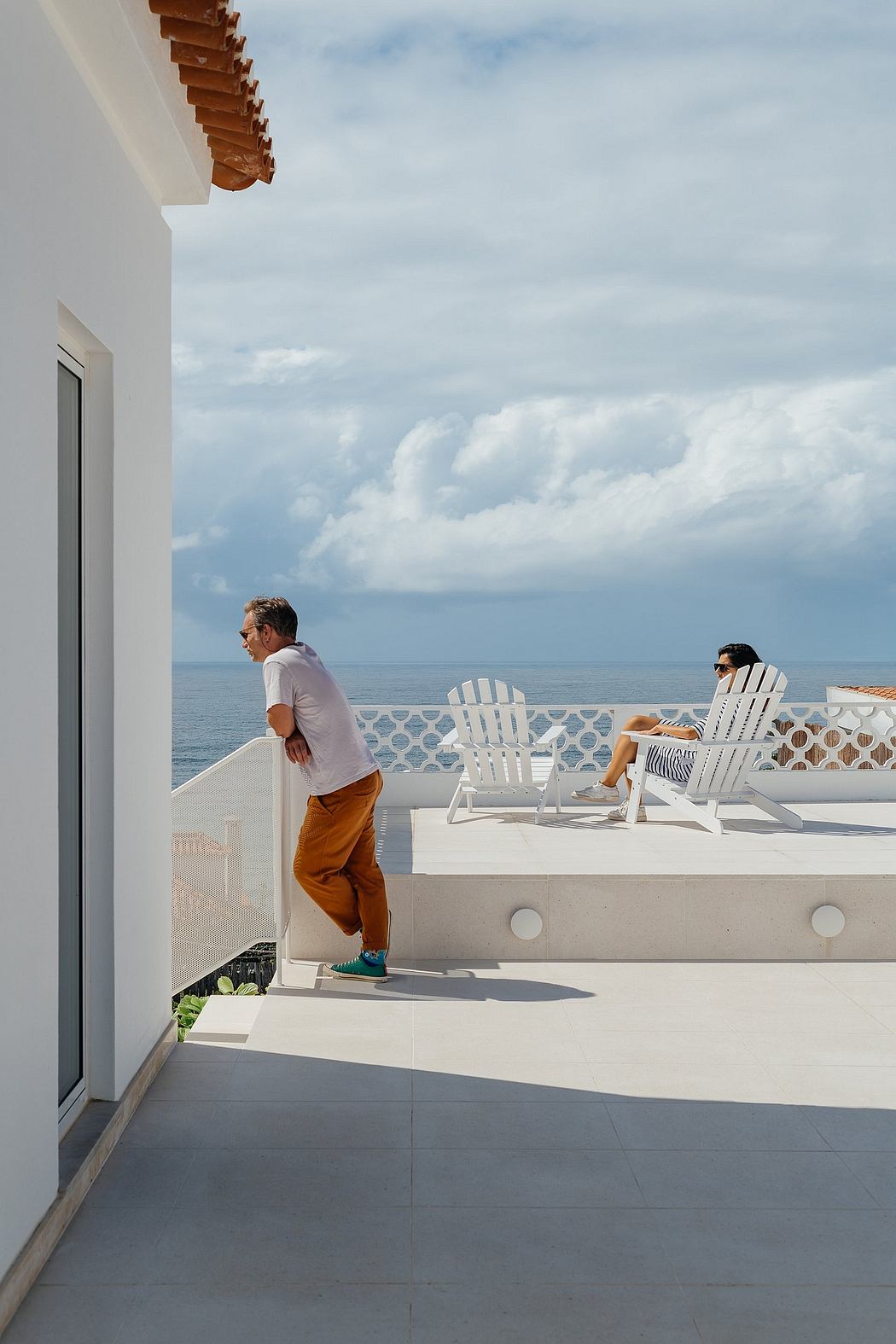 Oceanfront terrace with two people and white loungers