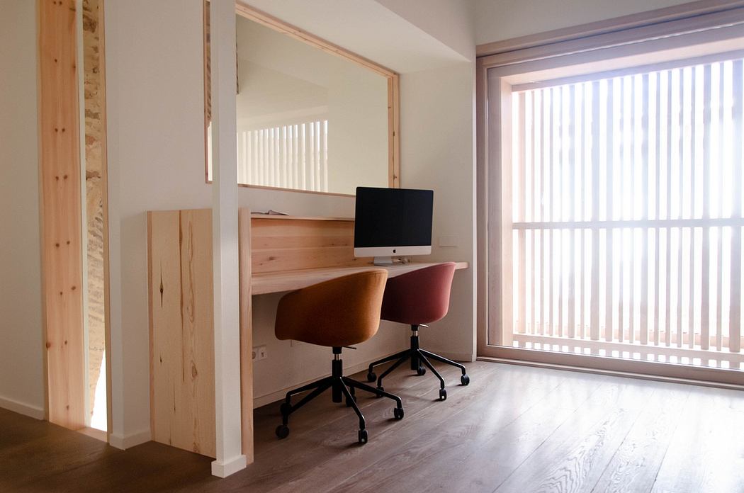 Minimalist home office with wooden desk, brown chair, and large window with blinds
