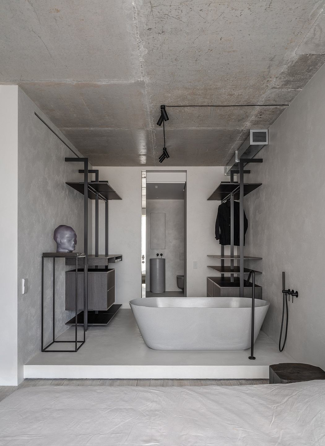 Modern minimalist bathroom with freestanding tub and exposed concrete ceiling.