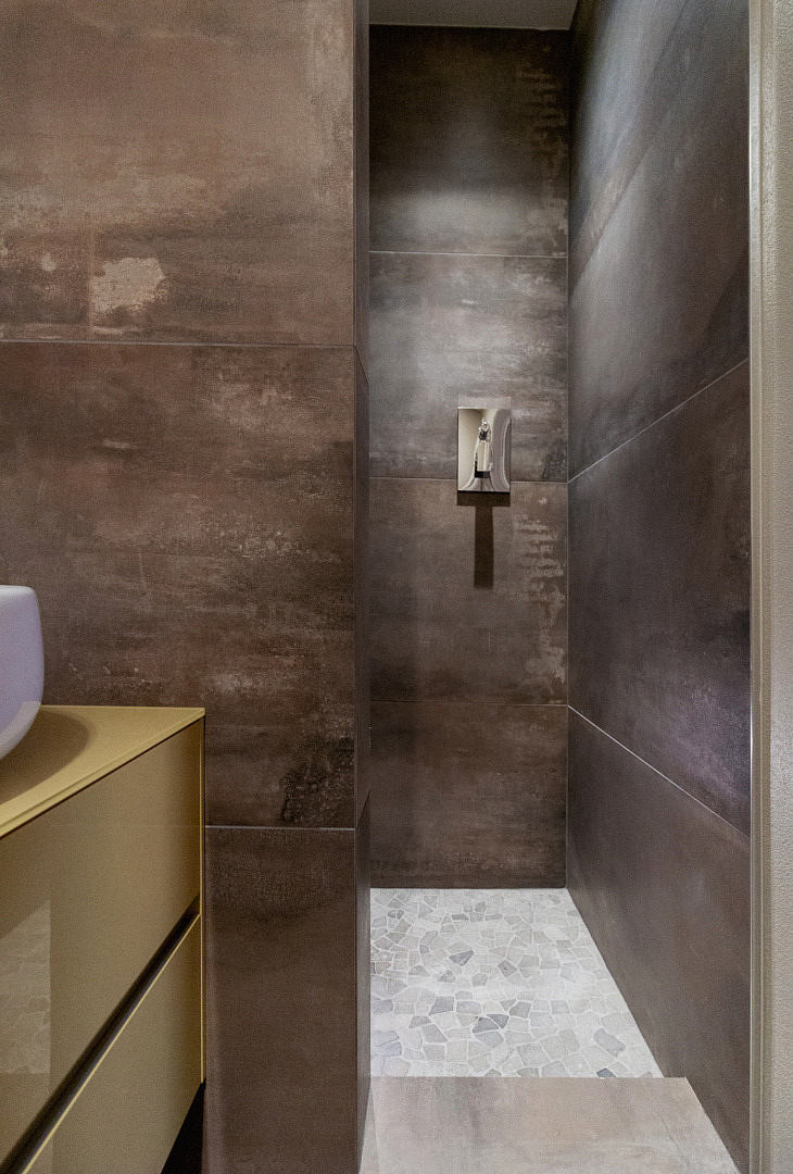 Modern bathroom with textured brown walls and patterned floor tiles.