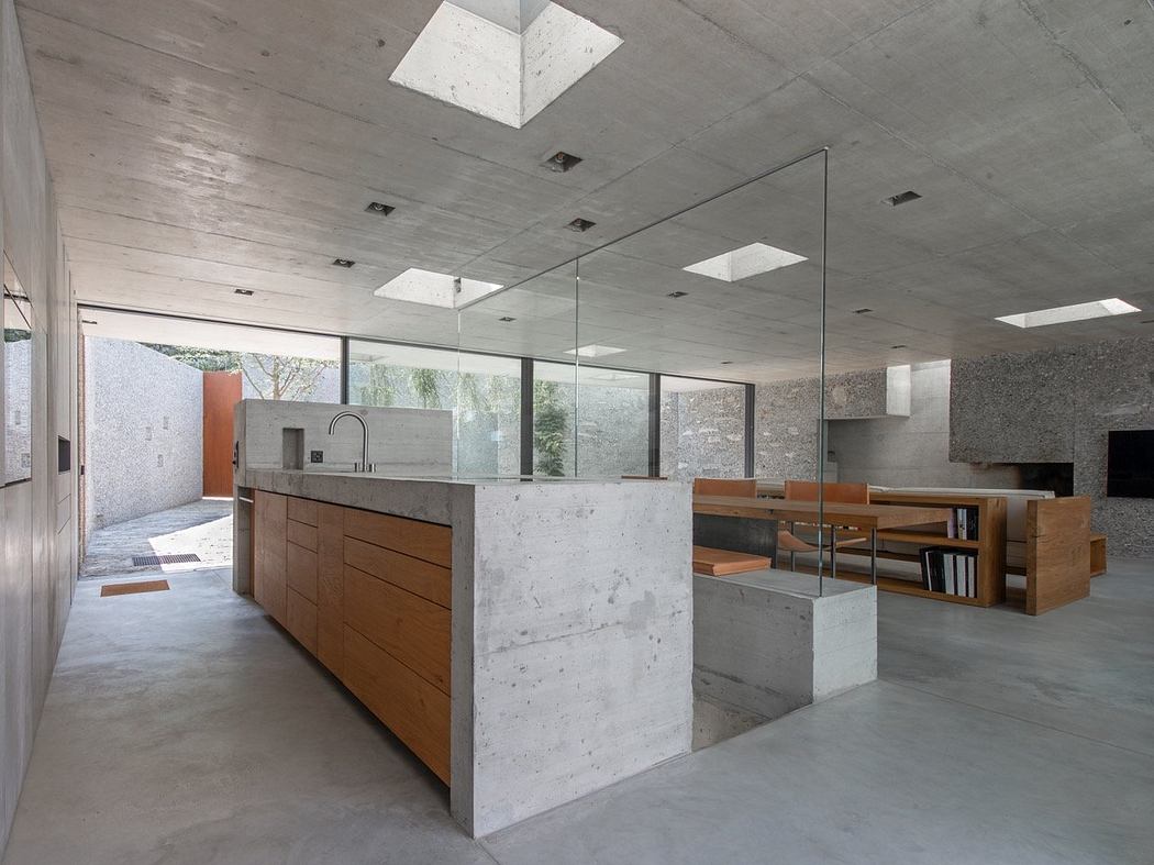 Minimalist concrete interior with large glass panels and wooden accents.