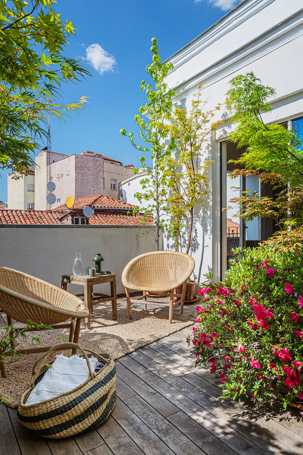 Cozy outdoor patio with chairs, plants, and open French doors.