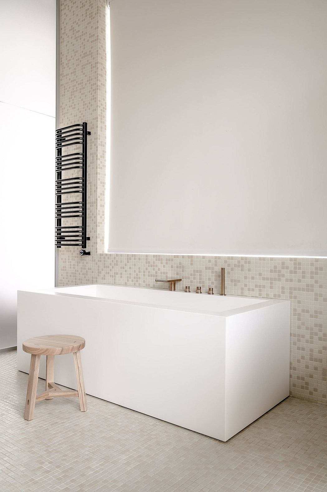 Modern bathroom with white tub, mosaic tiles, and wooden stool.