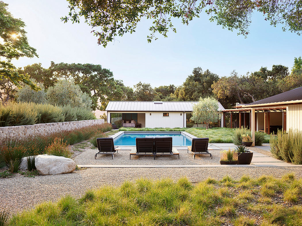 Backyard with pool, loungers, and modern house in a natural setting.