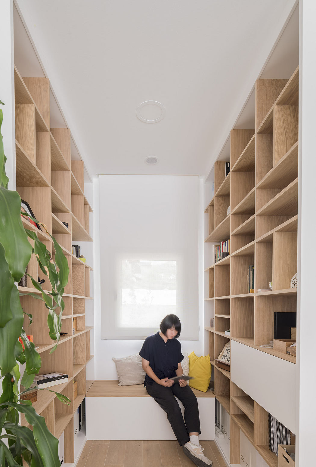 Bright minimalist room with wooden shelving and a seated person.