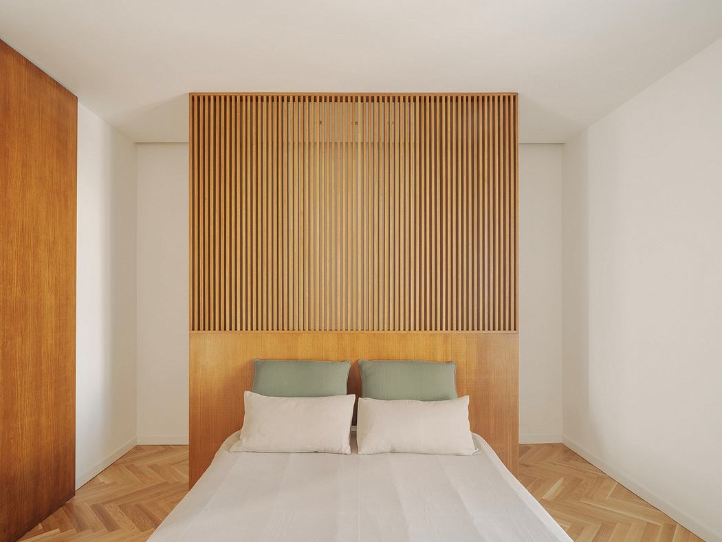 Minimalist bedroom with wooden slatted wall feature above the bed.
