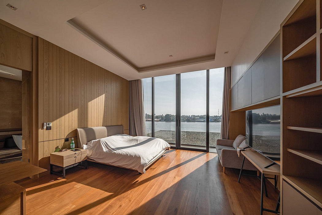 Contemporary bedroom with panoramic window overlooking a river.