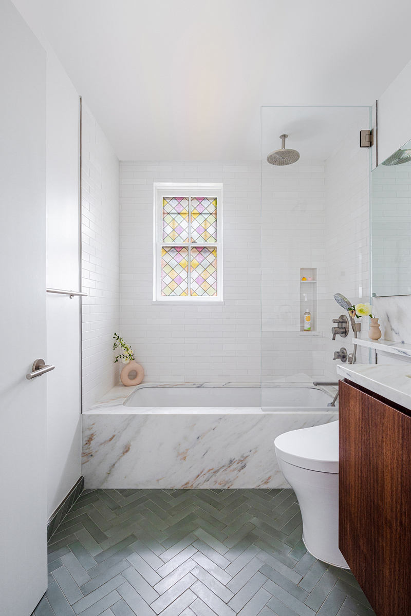Contemporary bathroom with herringbone floor and stained-glass window.