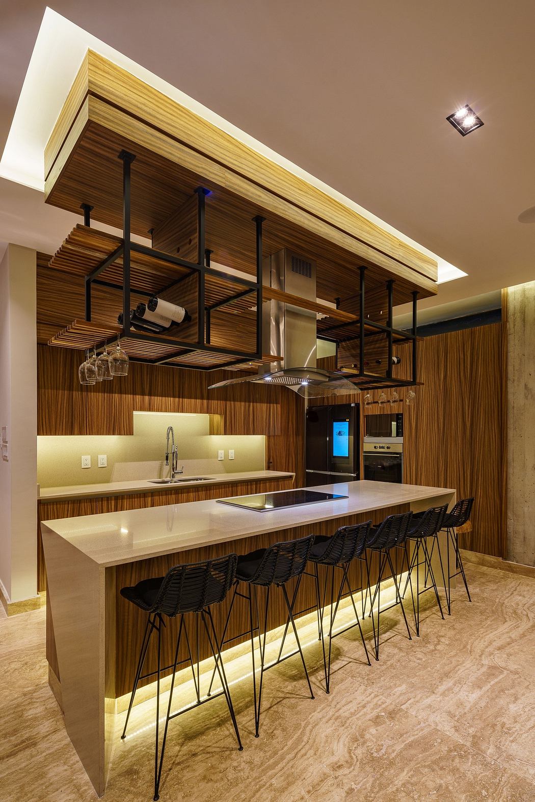 Modern kitchen with wood paneling, hanging pots, island, and under-counter lighting