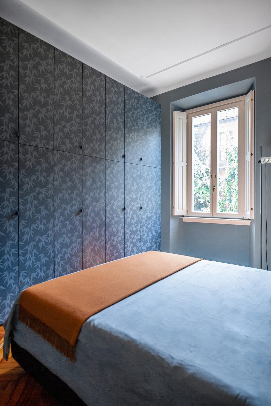 Contemporary bedroom with patterned wall and blue bedspread.
