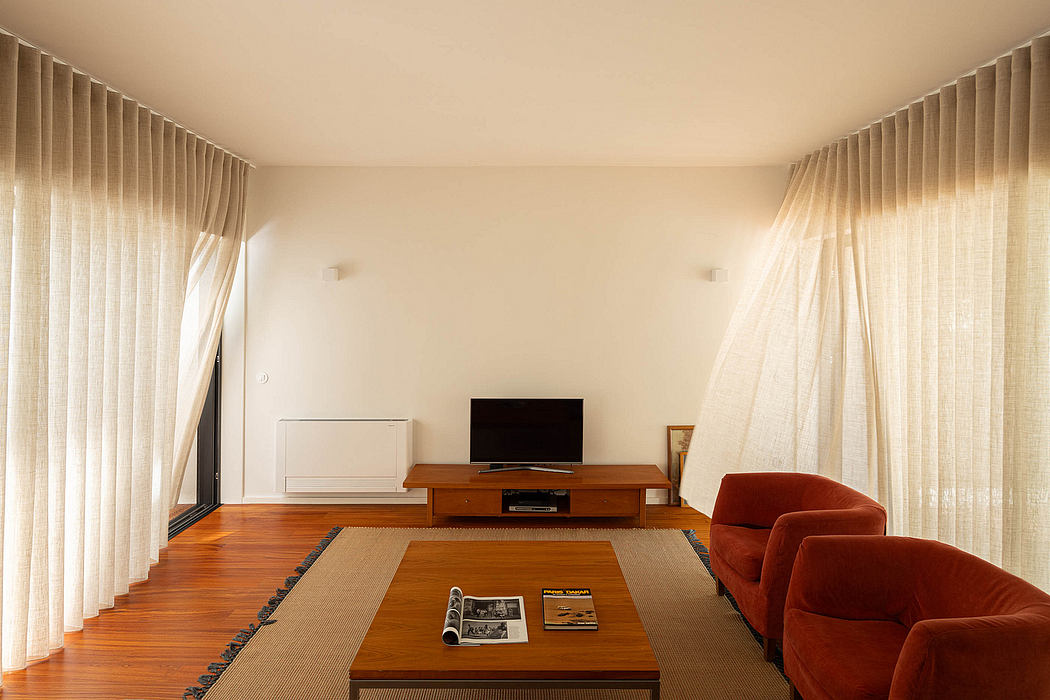 Contemporary living room with warm wood floors and sheer curtains.