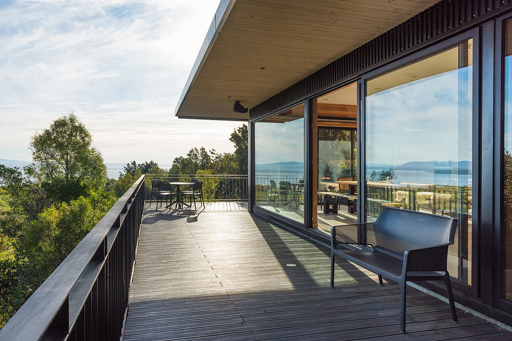 Modern house deck with glass windows overlooking scenic view.