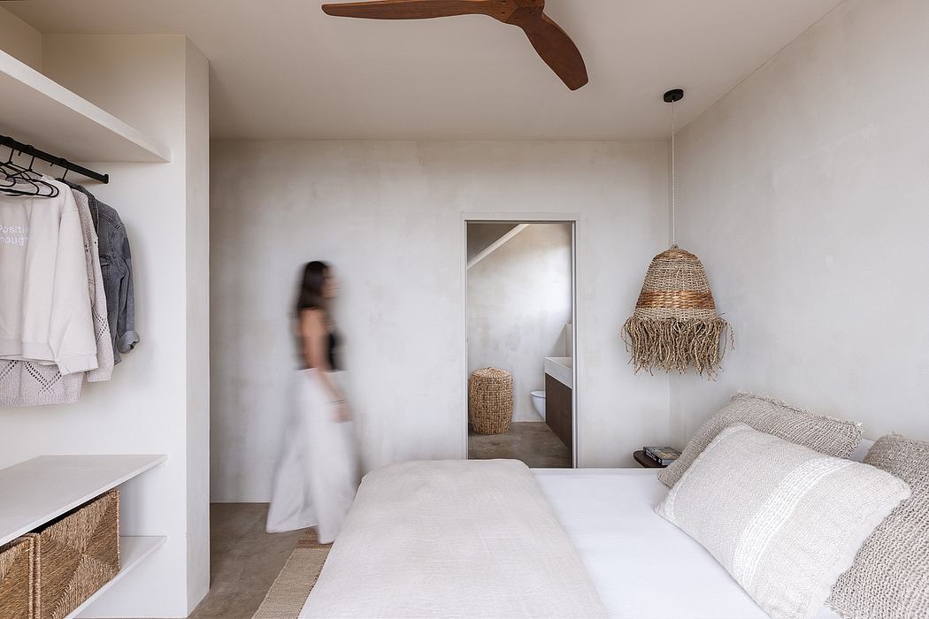 Minimalist bedroom with white walls and neutral accents, featuring a ceiling fan and open