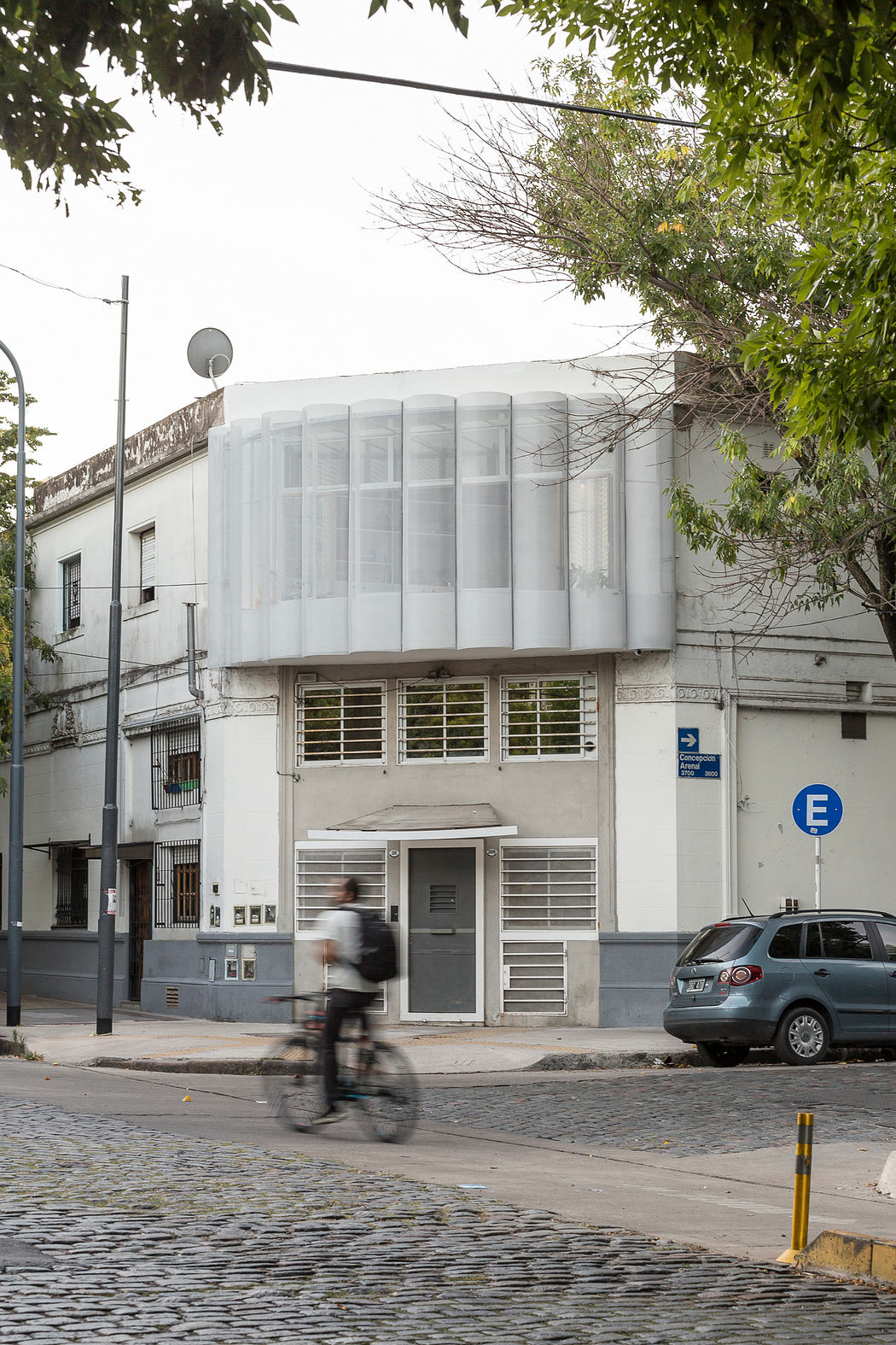 Modern white building with rounded corner facade, cyclist in motion blur.