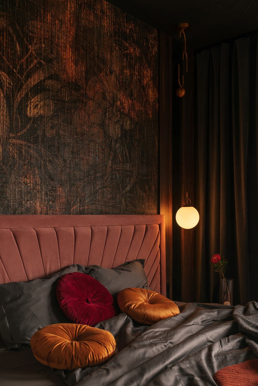 A cozy bedroom corner with a velvet headboard, decorative pillows, and mood lighting