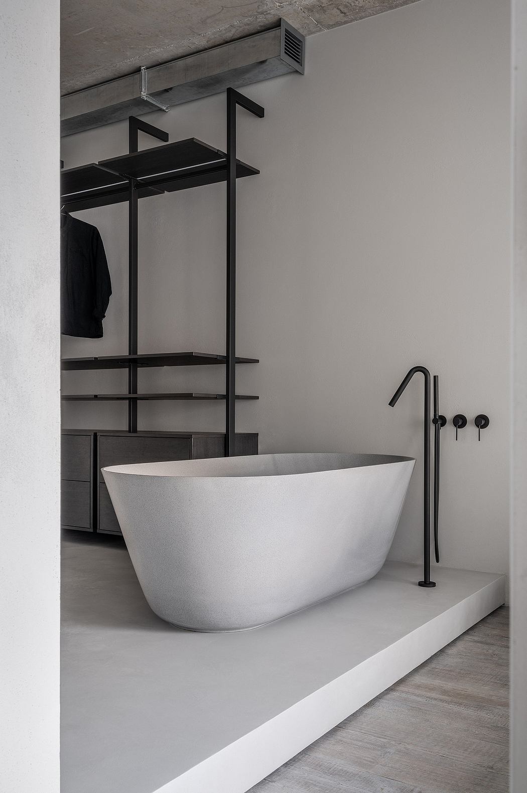 Minimalist bathroom with a standalone oval bathtub and monochrome palette.