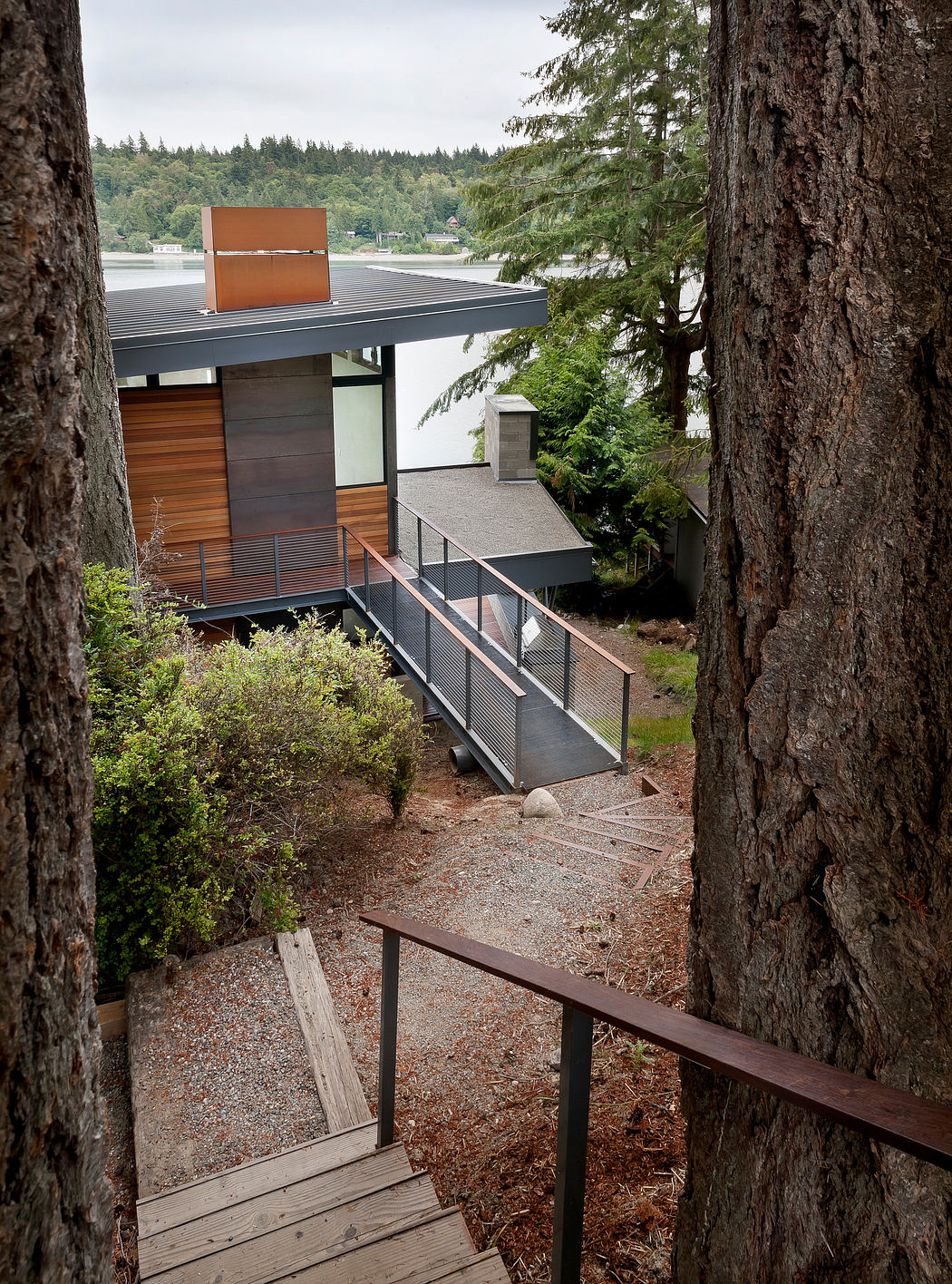 Modern house with a metal ramp entrance framed by trees.